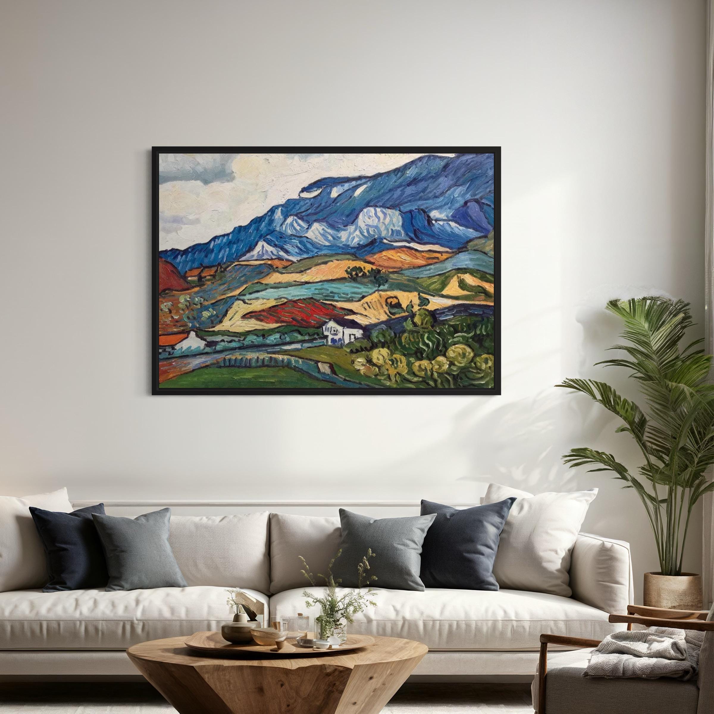 May include: A framed painting of a landscape with a blue, green, and brown color scheme. The painting depicts a mountain range in the background, with a small house and trees in the foreground. The painting is framed in black and is hanging on a white wall.