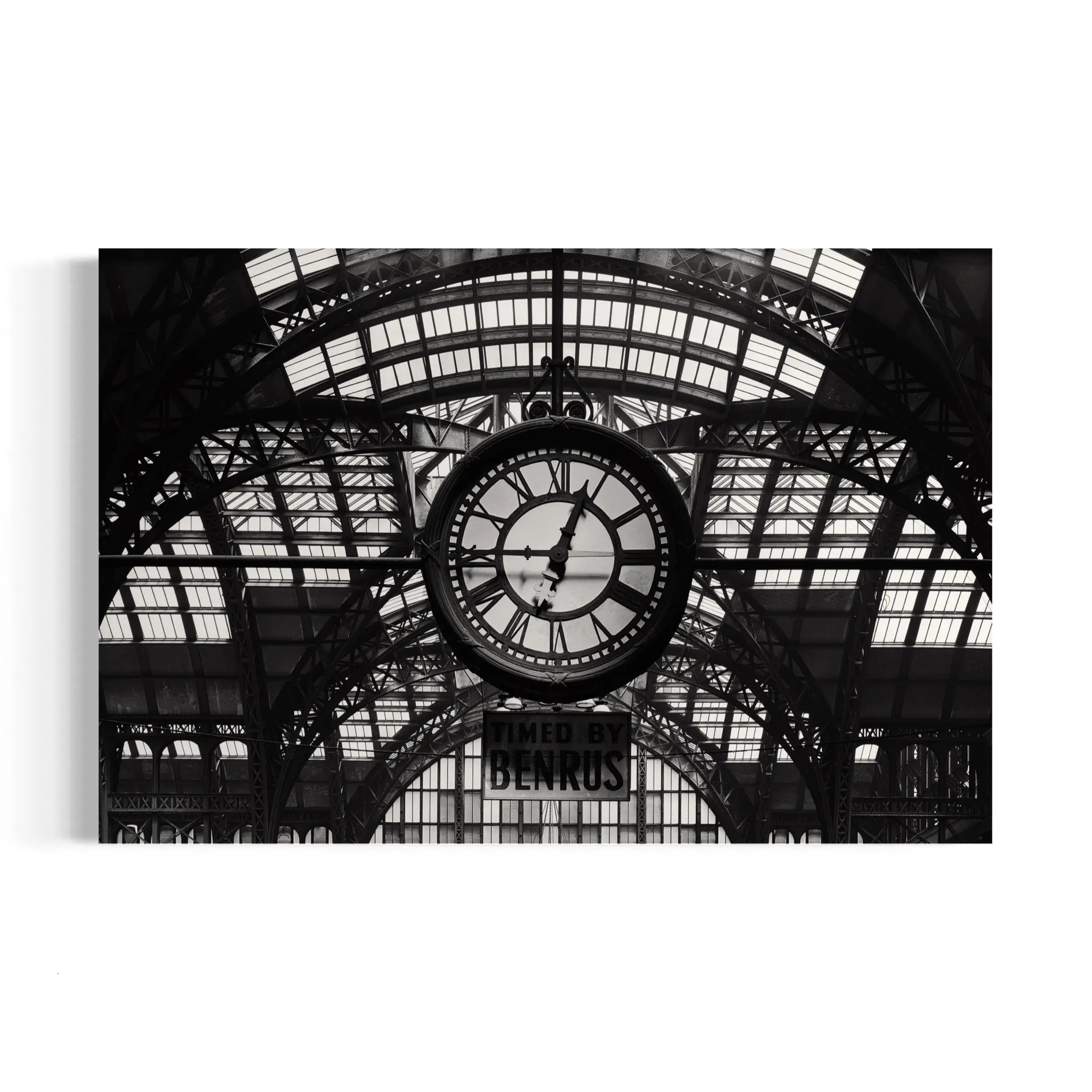 a black and white photo of a clock in a train station