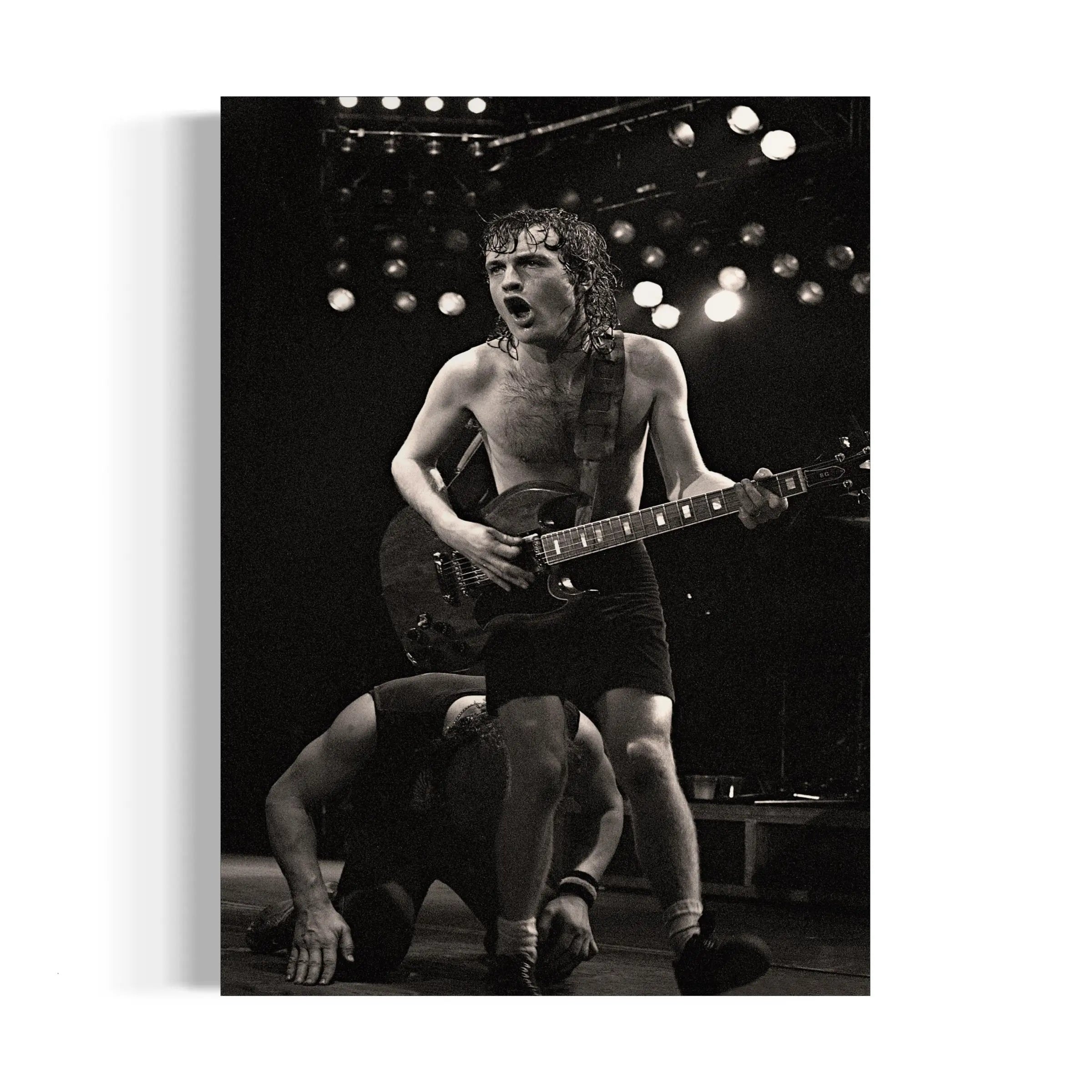 a black and white photo of a shirtless man playing a guitar