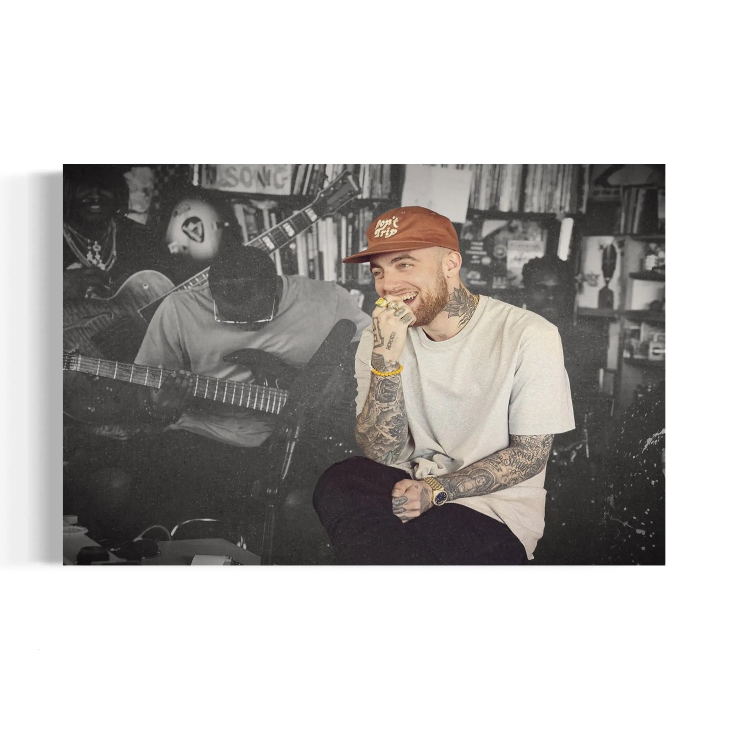 a man with a beard and tattoos sitting in front of a guitar